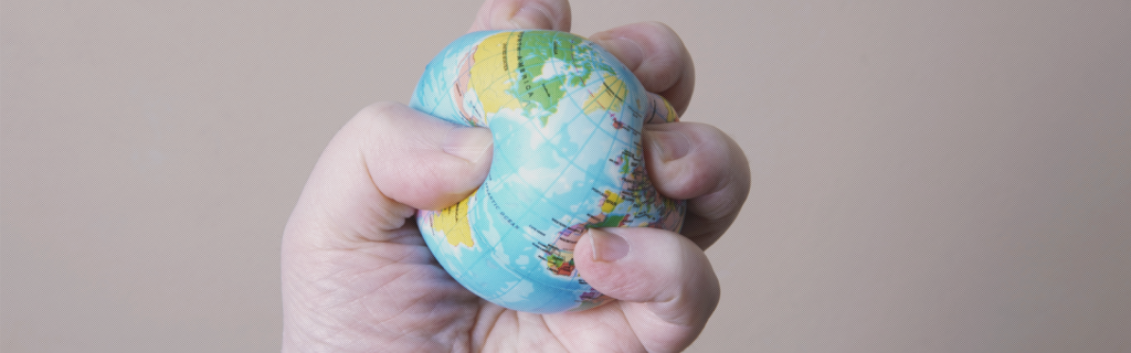 Hand holds a stress ball in the shape of a globe and squeezes firmly.