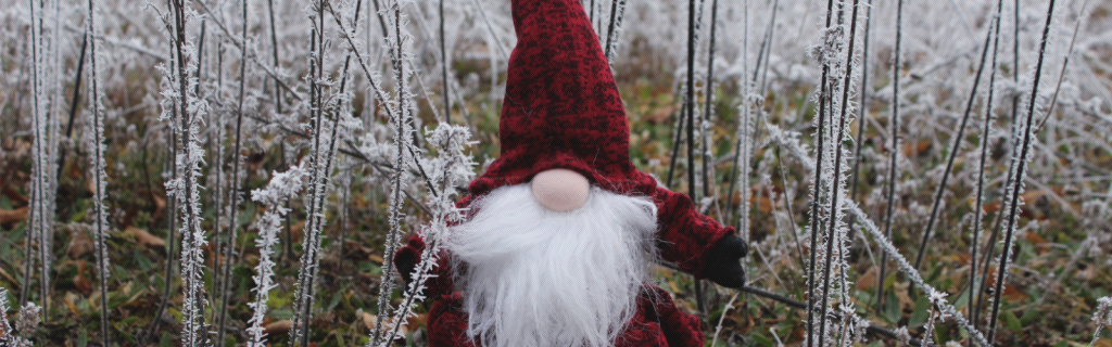 Christmas elf stands in the forest. All the branches are covered in hoarfrost.