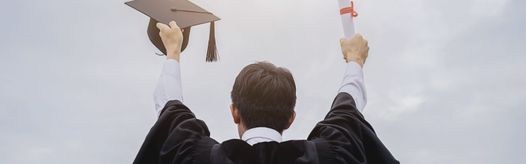 Man with certificate and graduation cap throws his arms up in the air