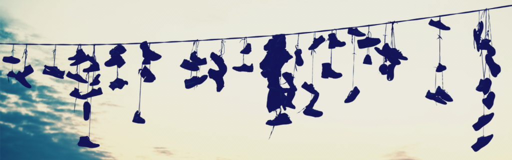 Soccer boots and sneakers hang from a washing line stretched across the picture